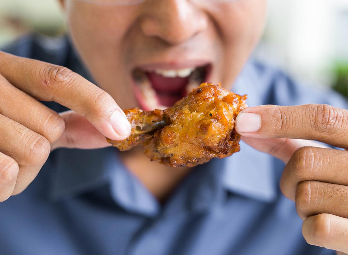 man eating a fried chicken wing