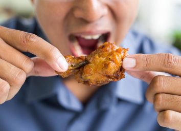 man eating a fried chicken wing