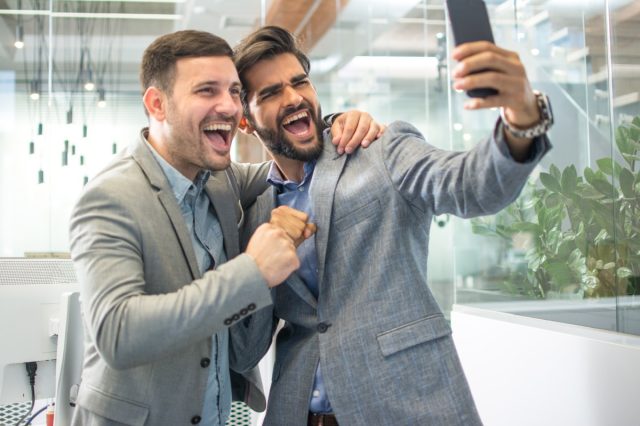 Two men in business wear taking a selfie photo in office