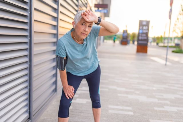 Portrait of athletic mature woman resting after jogging in park at sunset
