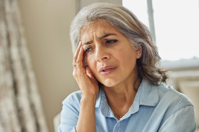 Mature Woman At Home Suffering From Headache Or Memory Loss