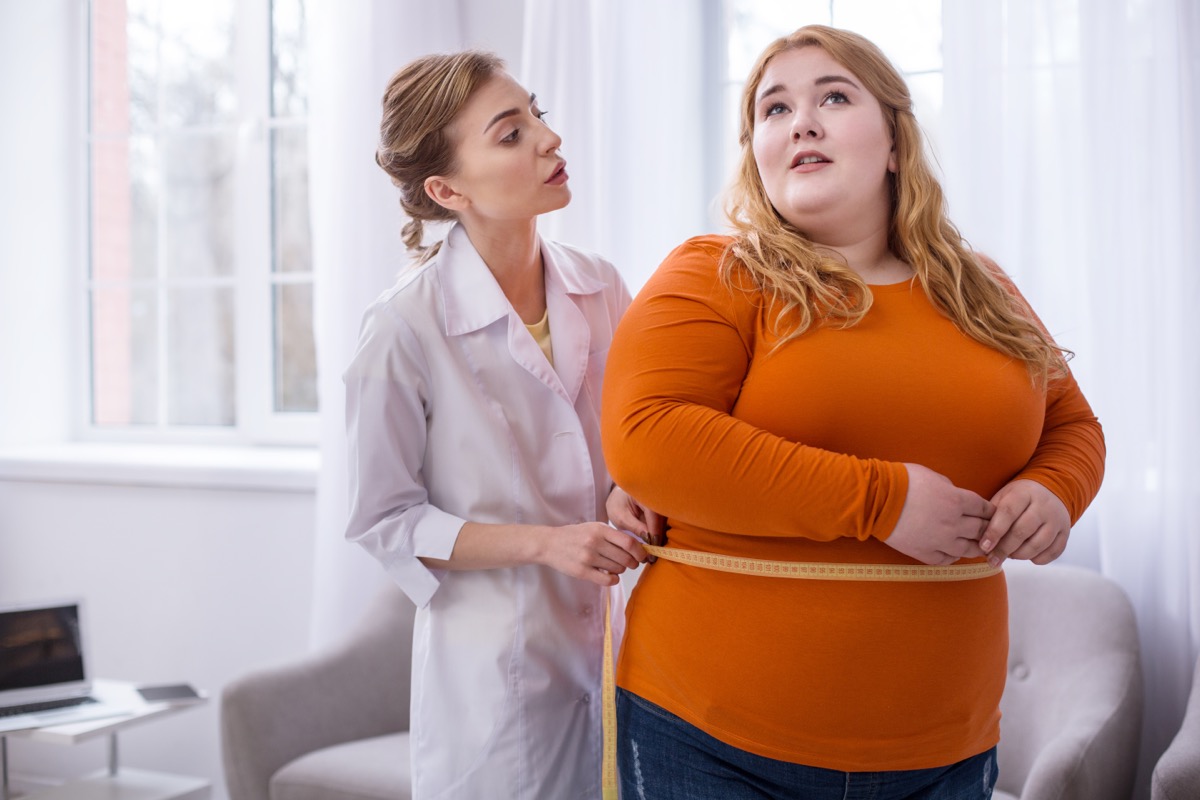 Doctor talking with an obese woman and measuring her.