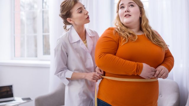 Doctor talking with an obese woman and measuring her.