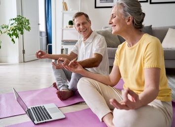 older couple doing yoga in front of a laptop