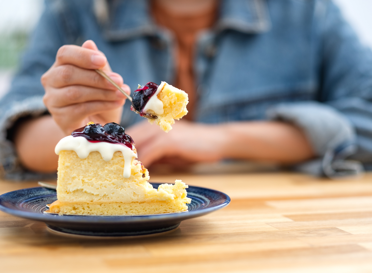 woman eating blueberry cheesecake