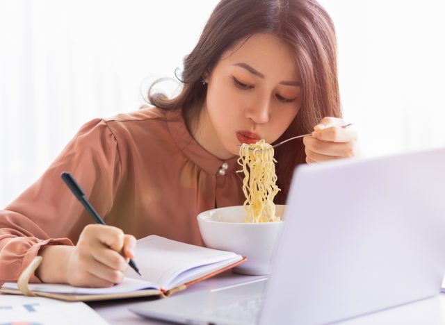woman eating noodles and writing