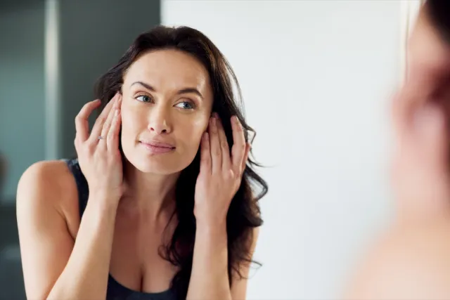 Woman admiring her face in the bathroom mirror.