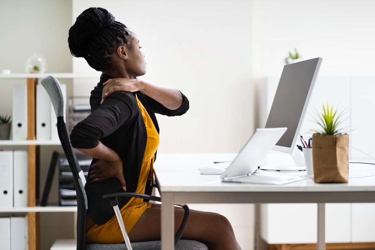 young woman sitting at desk with back pain