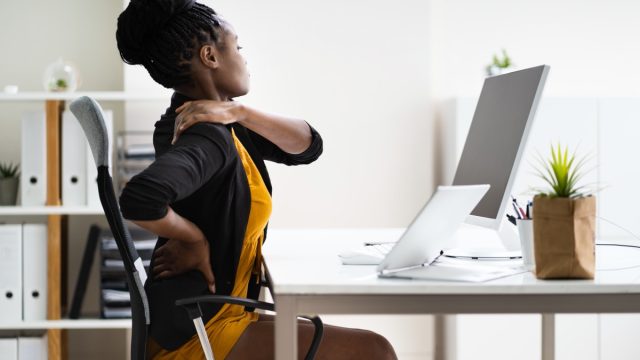 young woman sitting at desk with back pain