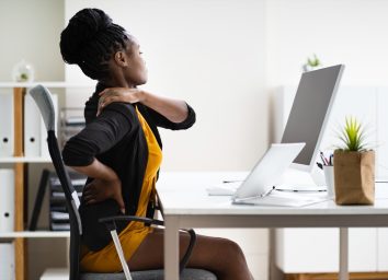 young woman sitting at desk with back pain