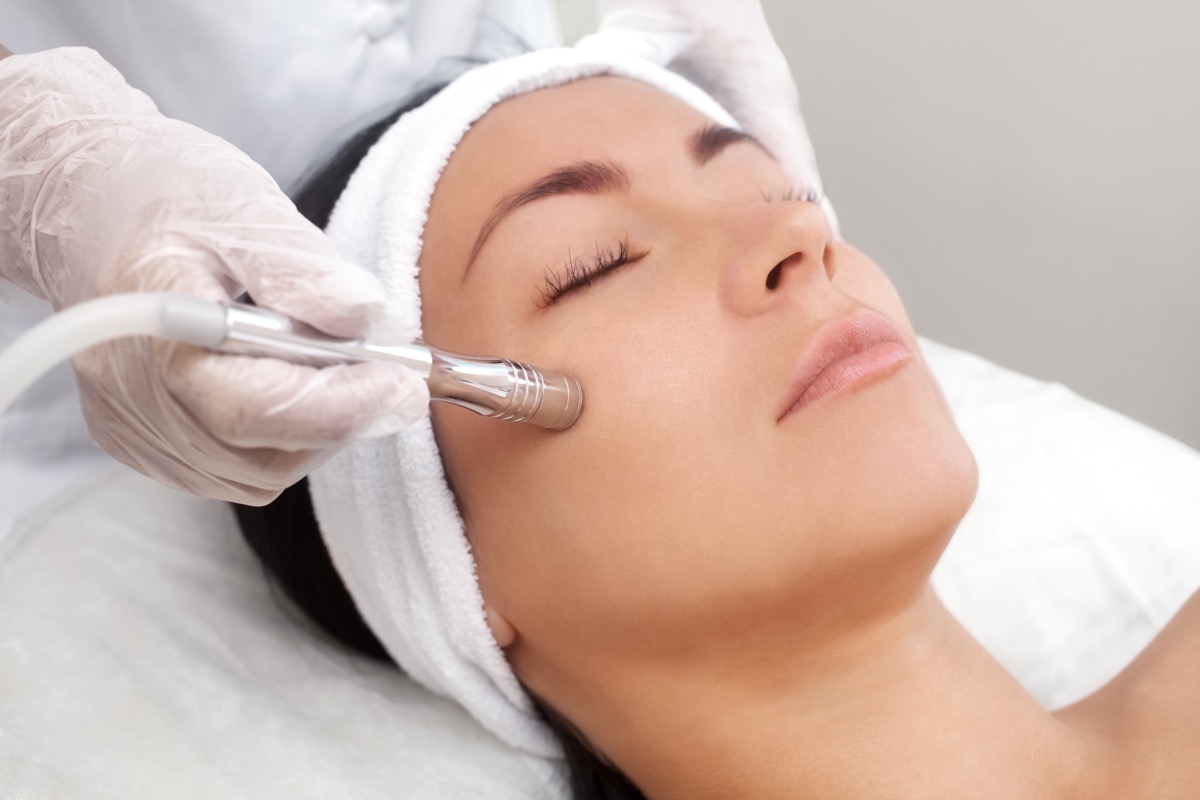 Cosmetologist makes the procedure Microdermabrasion of the facial skin of a beautiful, young woman in a beauty salon.
