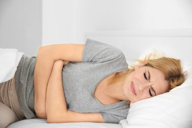 Young woman suffering from pain on bed