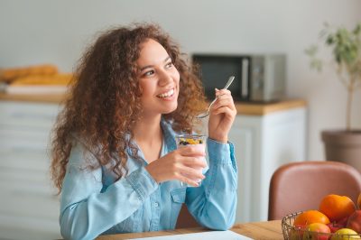 young woman eating yogurt in kitchen