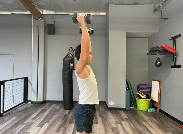trainer doing shoulder press with weights