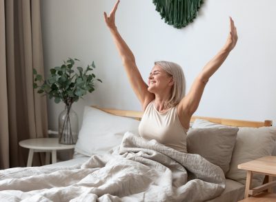 happy woman stretching in bed