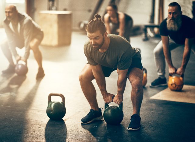 man lifting weights at gym class while squatting