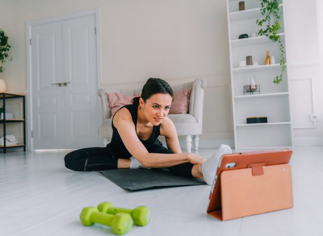 woman stretching doing a workout on tablet