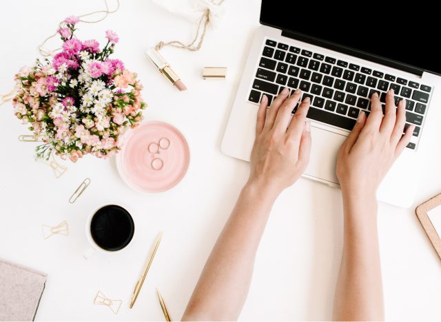 woman's desk with laptop and flowers