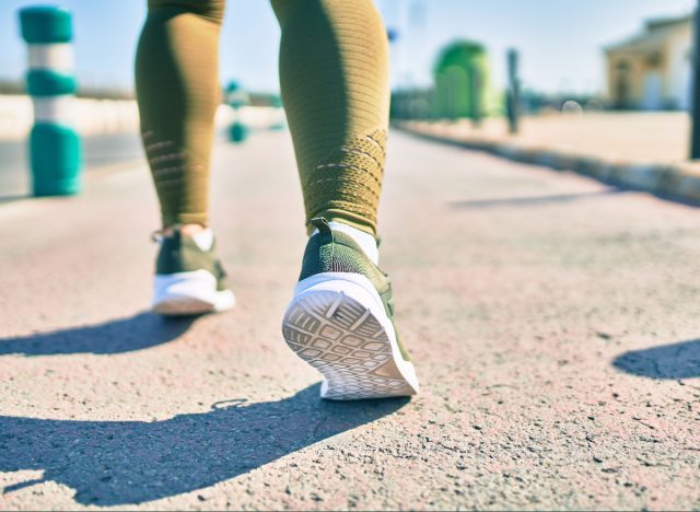 close-up woman's green running sneakers on pavement