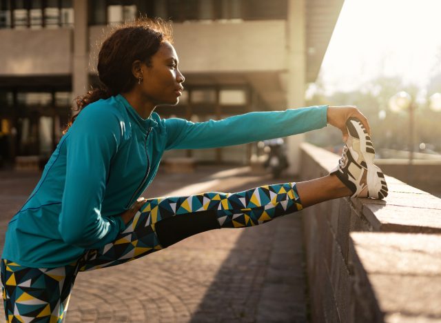 female runner in workout attire stretching legs