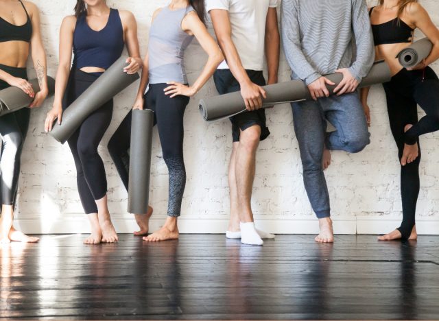 group of people in workout attire holding yoga mats