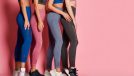 group of women lined up in workout leggings, sports bras, and sneakers in front of pink backdrop