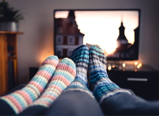 close-up of couple's feet in cozy socks in front of TV