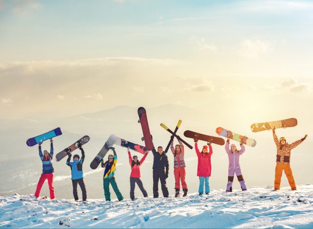 group of snowboarders and skiers holding up their boards and skis