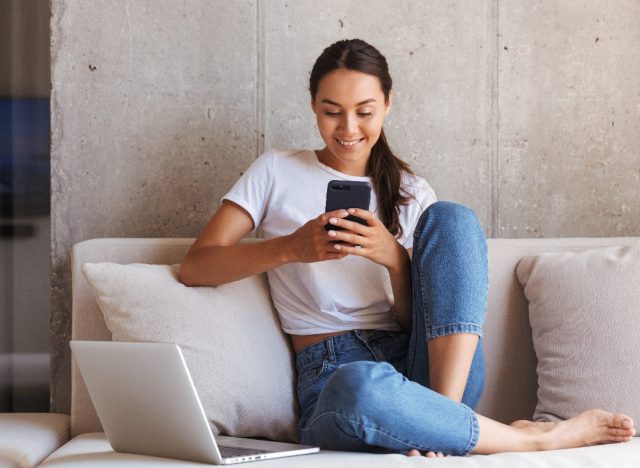 woman playing a game on her cell while sitting on couch