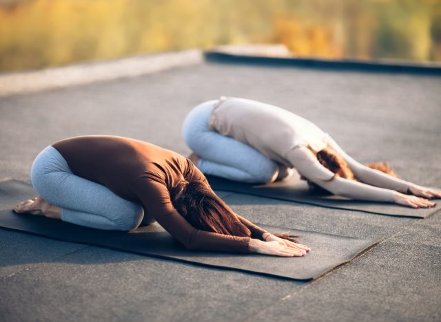 deux femmes en posture d'enfant sur des tapis de yoga