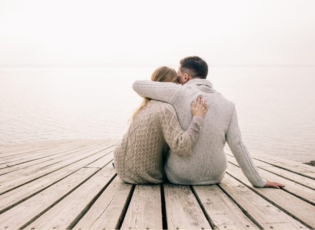 couple embracing while sitting on dock