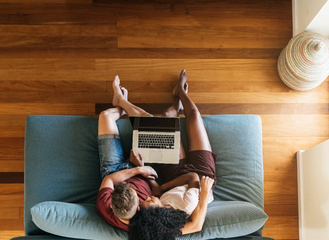 couple cuddling on couch with laptop doing research