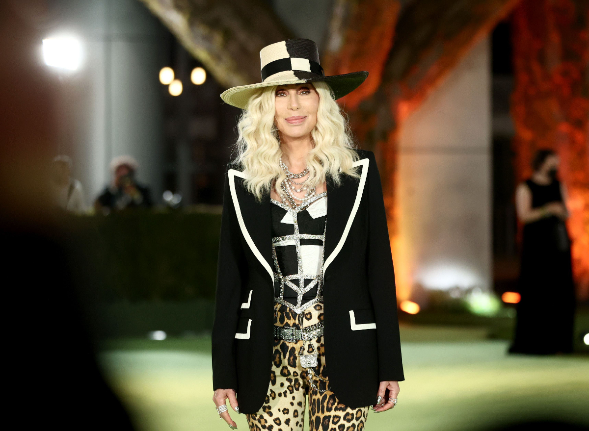 Cher smiles at an event dressed in leopard pants