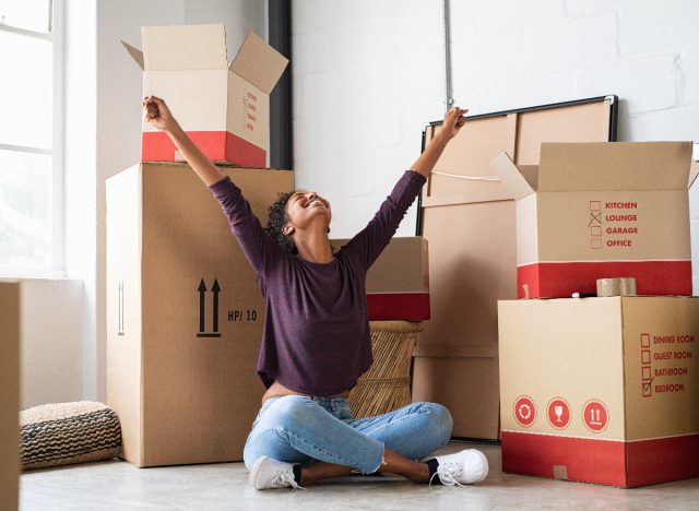 happy woman surrounded by moving boxes in new apartment