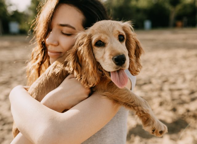 woman holding puppy on the beach