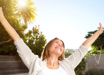 happy woman stretching arms in sunshine