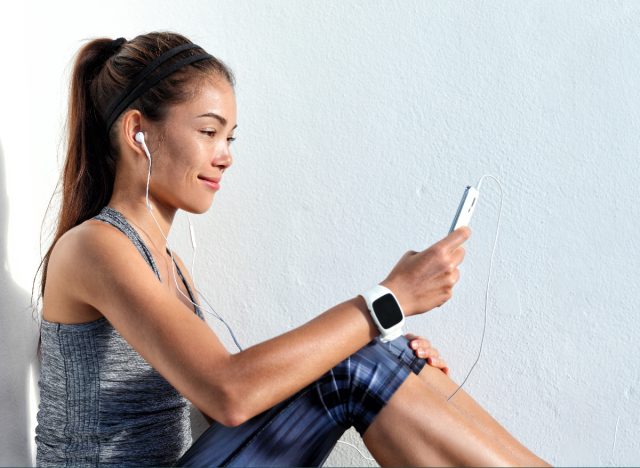 woman wearing fitness watch checking iPhone