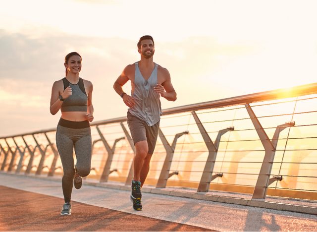 couple runs at sunset on city bridge