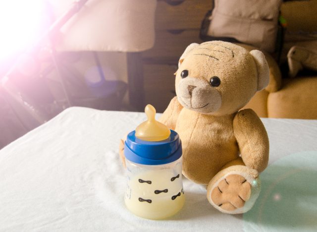 milk bottle next to teddy bear in baby's room