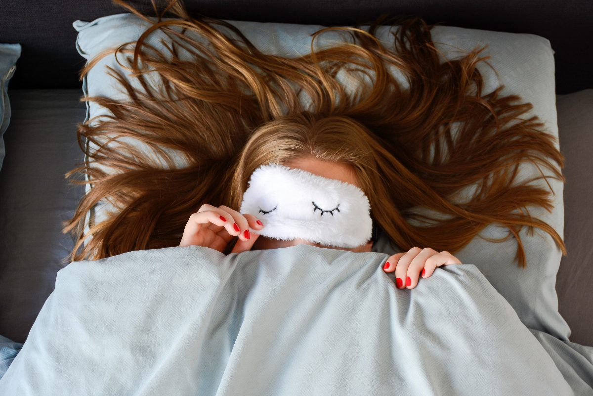 woman wearing fuzzy sleep mask in bed