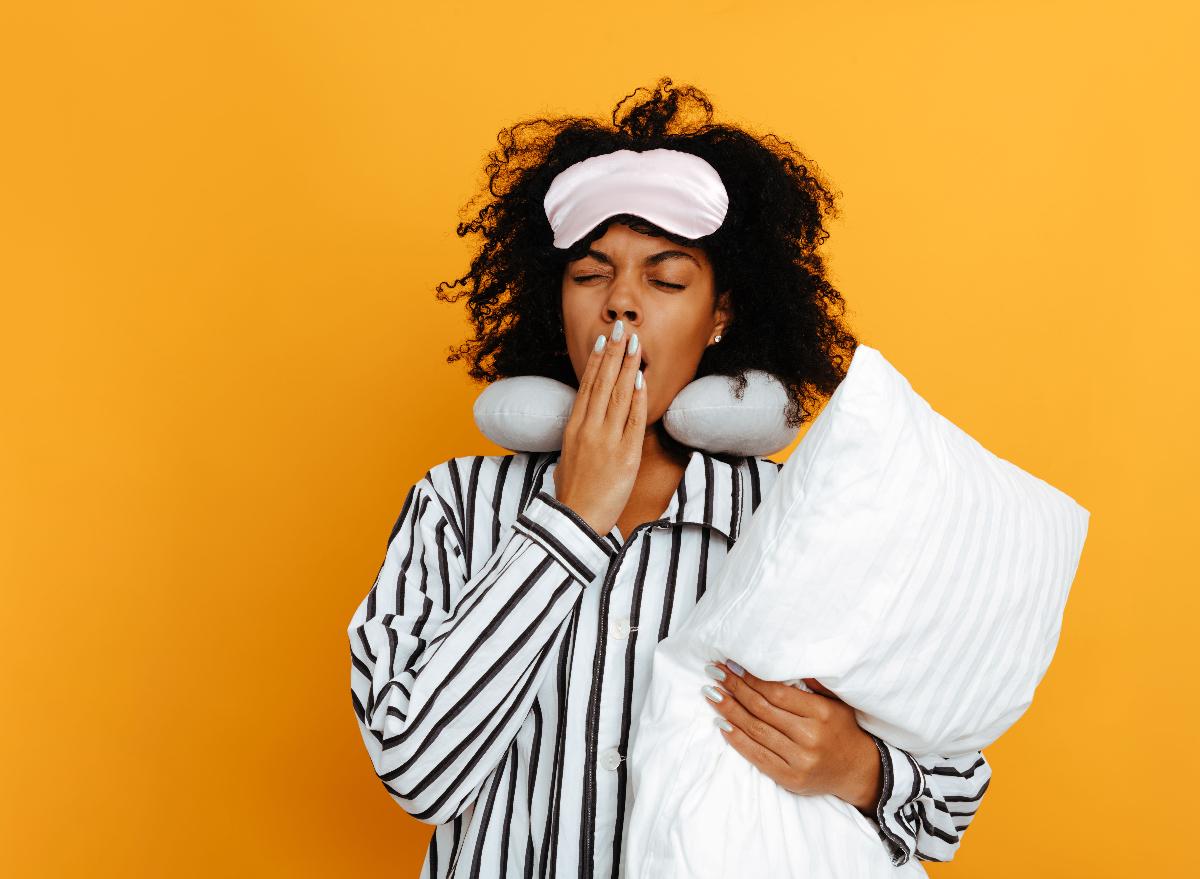 woman in pjs yawning and holding pillow