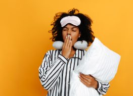woman in pjs yawning and holding pillow
