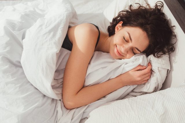 woman sleeping happily in plush bed