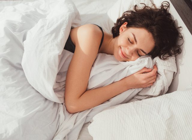 femeie care doarme fericită în pat de pluș