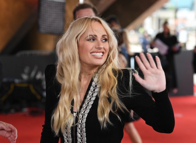 Rebel Wilson smiling and waving at red carpet event