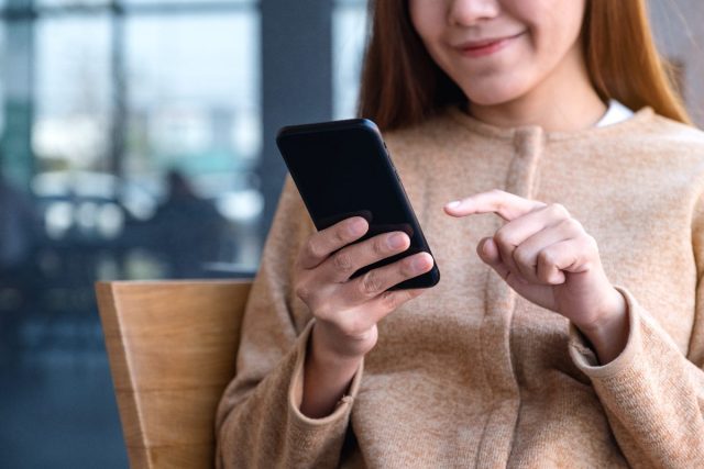 woman smiling and typing on phone