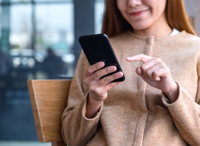 woman smiling and typing on phone