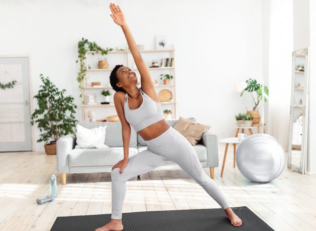 happy woman doing yoga pose in bright living room