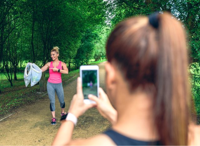 woman in fitness attire poses with trash bags while plogging