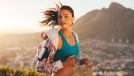woman jogs at sunset on hill overlooking city